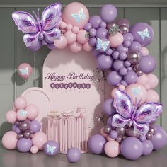 a birthday arch with balloons and butterflies on it