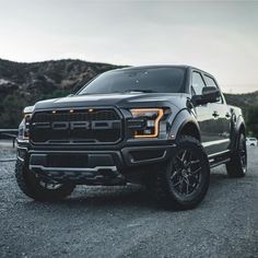 a black truck parked on top of a gravel road