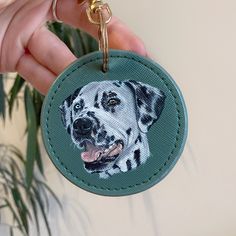 a hand holding a keychain with a photo of a dalmatian on it