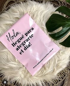 a pink bag sitting on top of a white rug next to a green leafy plant