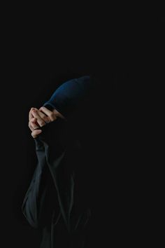 a person with their hands on the back of his head, in front of a black background