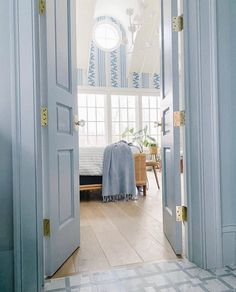 an open door leading to a bedroom with a bed in the corner and blue curtains