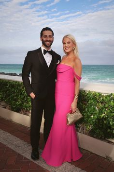 a man in a tuxedo standing next to a woman in a pink dress