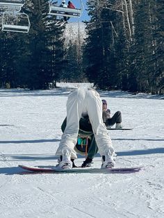 a person on a snowboard in the snow with a ski lift above them and trees in the background