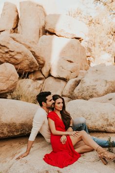 a man and woman sitting on rocks in the desert