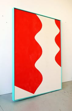 a large red and white painting sitting on top of a floor next to a wall