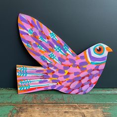 a colorful paper bird sitting on top of a wooden table