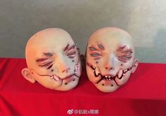 two creepy looking masks sitting on top of a red table