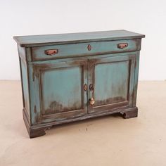 an old blue cabinet with two doors and handles on the bottom, sitting in a room