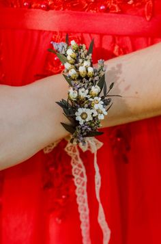 a woman in a red dress is wearing a flower bouquet on her arm with lace