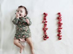 a baby laying on the floor next to two letters that spell out love and roses