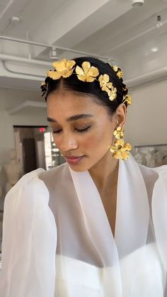 a woman wearing a white blouse and yellow flowers in her hair