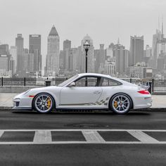 a white sports car parked in front of a city skyline