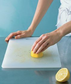 a woman is peeling a lemon on top of a white cutting board with a knife