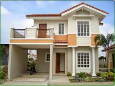 a white and orange two story house with a motorcycle parked in front of the door