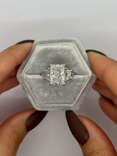 two hands holding an engagement ring in a velvet box