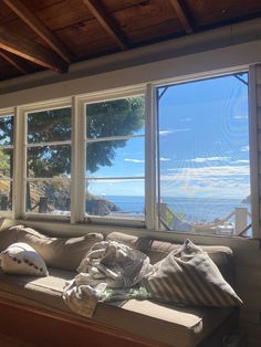 a window seat with pillows on it in front of a large window overlooking the ocean