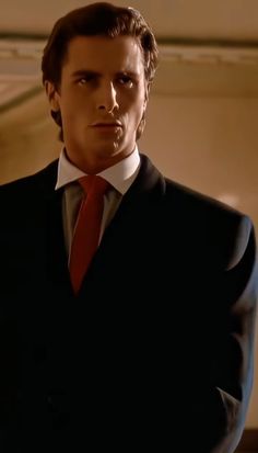 a man in a suit and red tie is looking at the camera with serious expression on his face