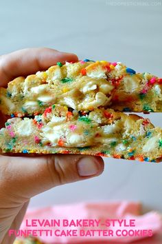 a person holding up a cookie with sprinkles and white frosting on it