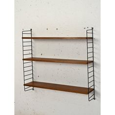 three wooden shelves on the wall, one with metal bars and two without shelving