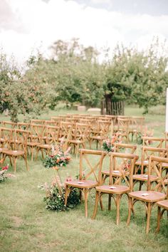 rows of wooden chairs sitting in the middle of a field with flowers on each seat