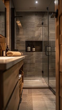 a walk in shower sitting next to a sink and a wooden cabinet with towels on it