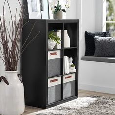 a black bookcase filled with books next to a white vase and window sill