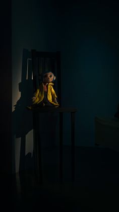 a stuffed animal sitting on top of a wooden chair next to a dark room filled with furniture