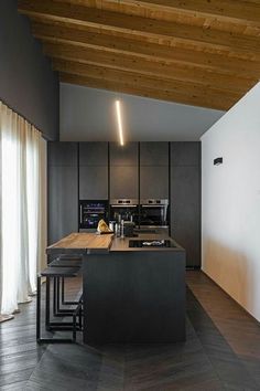 a kitchen with an island and wooden ceilinging in the center, along with two stools