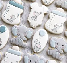 cookies decorated to look like elephants and baby items are on a marble countertop with white icing