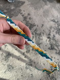 a hand holding an odd colored rope with two strings attached to it and another string on the end