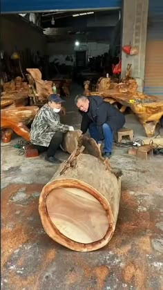 a man standing next to a large piece of wood