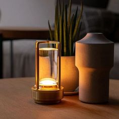 a table with a lamp on top of it next to a vase and potted plant