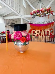 a graduation cap on top of a disco ball with flowers in the center and tassels hanging from the ceiling