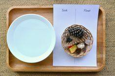 a plate and bowl on a wooden tray next to a place setting with pine cones