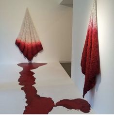 two red and white sculptures on display in an art gallery, one is upside down