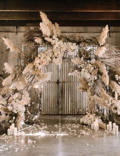 a wedding arch with flowers and candles in front of an open door at the end