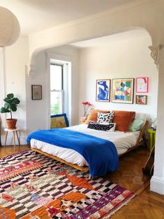 a bed sitting in the middle of a living room next to a large rug on top of a hard wood floor