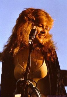 a woman with long red hair standing in front of a microphone