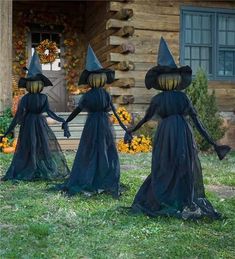 three black witches walking in front of a log cabin with pumpkins on the ground