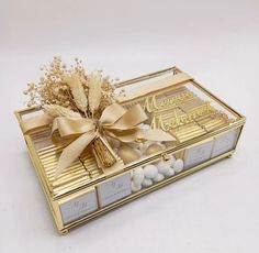 a gold box filled with lots of candies next to a bow on top of it