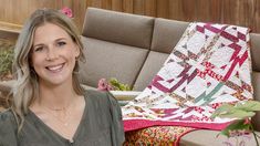 a woman sitting on a couch next to a quilted blanket and potted plant