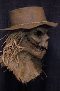 an old scarecrow mask with a hat and straw on it's head is shown