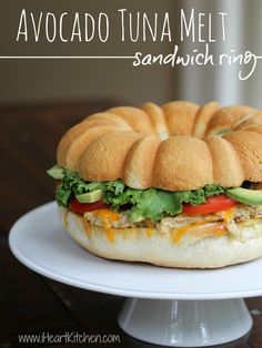 a sandwich sitting on top of a white cake plate with the words avocado tuna melt sandwich ring