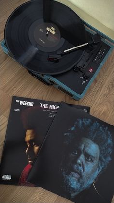 two vinyl records sitting on top of a wooden table