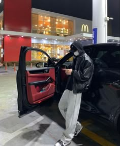 a person in a hoodie getting into a car