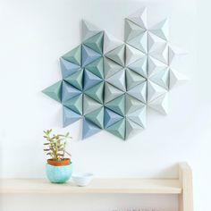 there is a small potted plant on the shelf next to an origami wall decoration