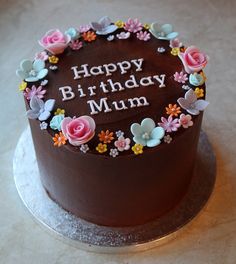 a chocolate birthday cake decorated with flowers and the words happy birthday mum written on it