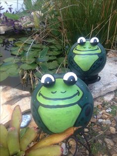 two green frog statues sitting on top of a rock