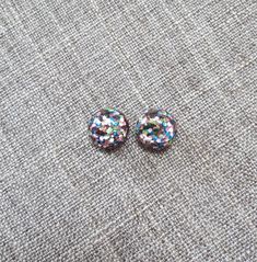 Rainbow glitter stud earrings in a round shape with your choice of posts! Super sparkly with a retro vibe. The earrings measure approx. 12mm in diameter. Resin with your choice of posts: 🔹 Standard metal posts: surgical steel, silver tone. 🔹 Titanium posts (with surgical steel backs): darker silver color. 🔹 Sterling silver posts & backings: .925 sterling silver 🔹 Plastic posts & backings: transparent plastic. 🔹 Clip on earrings: silver tone metal Stuff to know: - I do not guarantee Multicolor Round Clip-on Earrings For Party, Multicolor Round Clip-on Earrings, Silver Glitter Round Earrings, Glitter Round Earrings For Gifts, Kawaii Hair Clips, Rainbow Choker, Glitter Stud Earrings, Rainbow Confetti, Earrings Kawaii